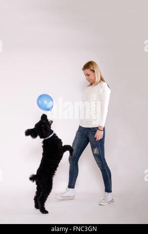 Jeune femme jouant avec un caniche noir. Banque D'Images