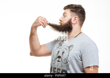 Profil de choqué se demande homme barbu tenant sa barbe sur fond blanc Banque D'Images