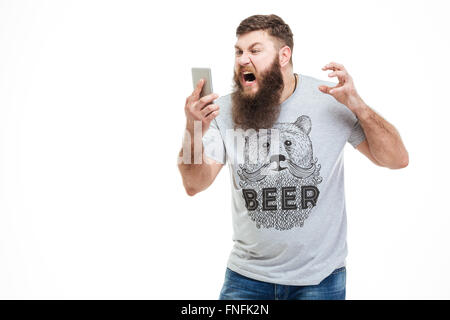 Homme en colère irritée avec barbe holding smartphone et crier sur fond blanc Banque D'Images