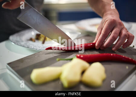 Les mains du chef chopping red hot chili sur une carte Banque D'Images