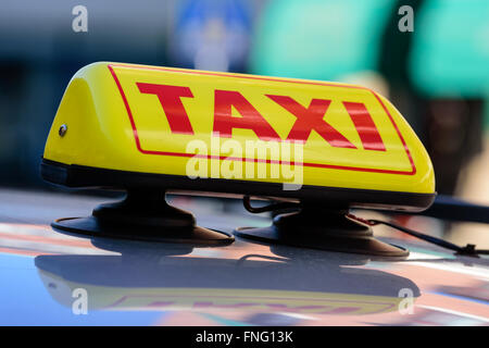 Un taxi jaune et rouge sur le toit d'une voiture. La garde est fixée à la toit de voiture avec ventouses. Banque D'Images