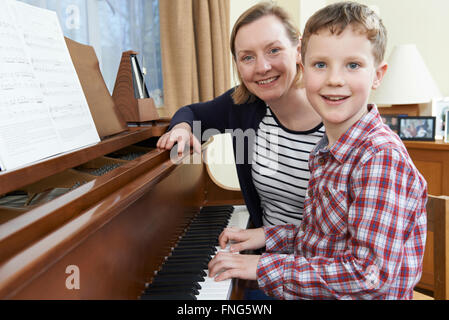 Garçon avec le professeur de musique ayant cours à Piano Banque D'Images