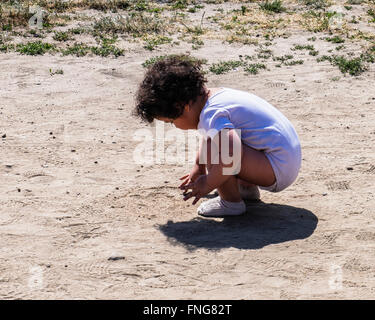 Jeune enfant dessin dans le sable d'une chaude journée d'été dans Mauerpark, un parc public. Berlin Banque D'Images