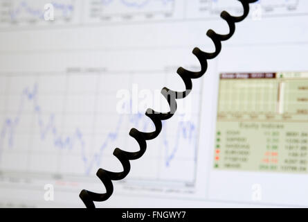 Des graphiques avec des données financières sur le moniteur et câble téléphonique Banque D'Images