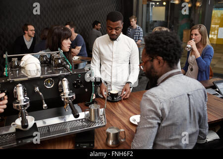 Homme africain avec cappucino au comptoir d'un café moderne Banque D'Images