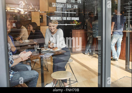 Femme vue à travers le verre en souriant tandis qu'un café avec un ami Banque D'Images