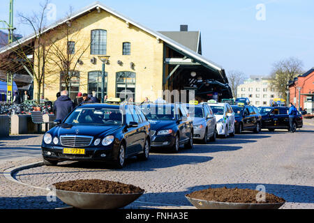 Lund, Suède - 12 mars 2016 : Une rangée de voitures de taxi, dans la file d'attente de passagers à l'extérieur de la gare. Des personnes réelles Banque D'Images