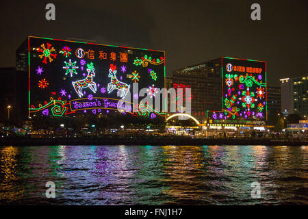 Meilleurs Vœux de fête géant lumières de Noël affichage la nuit sur les bâtiments du port de Victoria de Hong Kong Island Banque D'Images