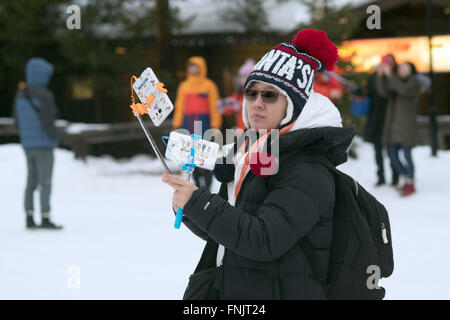 Un touriste asiatique avec deux bâtons selfies dans le village de Noël sur le cercle polaire à Rovaniemi, Laponie, 08 février 2016. Le Père Noël est un village de travail célèbre site touristique sur le nord du cercle polaire. Il peut être rencontré tous les jours. Courrier qui est envoyé à partir d'ici est le cercle polaire stamp. Photo : Peter Endig - AUCUN FIL SERVICE - Banque D'Images