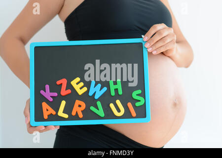 Pregnant woman holding Blackboard background avec blocs de couleur lettre Banque D'Images