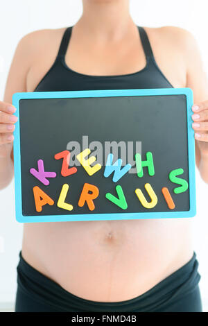 Pregnant woman holding Blackboard background avec blocs de couleur lettre Banque D'Images