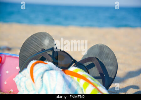 Accessoires de plage comme les lunettes, chaussons, serviettes, jouets sur le sable Banque D'Images