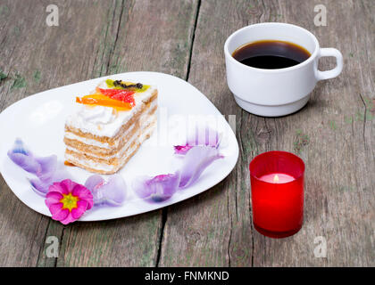 Plaque avec gâteau décoré avec des fleurs, du café et une bougie Banque D'Images