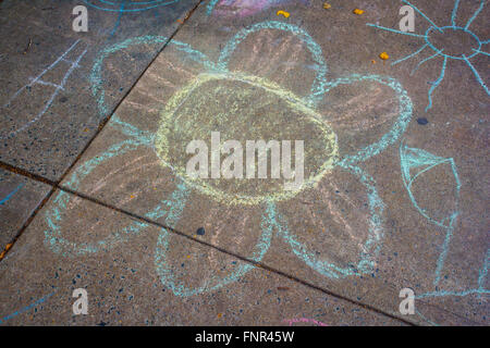 Un enfant est heureux grand dessin à la craie jaune et bleu d'une fleur sur un trottoir de la ville. Banque D'Images