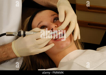 Jeune fille ayant son nettoyage des dents par un dentiste à l'aide d'une brosse à dents électrique. Banque D'Images