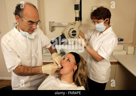 Une jeune fille en cours de préparation pour une radiographie dentaire par un dentiste et son assistant. Banque D'Images