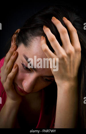 Une femme triste et déprimé tient sa tête dans ses mains. Banque D'Images