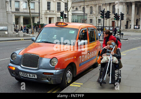 Londres, Royaume-Uni, 12 février 2016, black cab ramasse passager en fauteuil roulant à l'extérieur de la National Portrait Gallery. Le conducteur sort de Banque D'Images