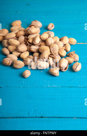 Les pistaches salées sur une table en bois bleu Banque D'Images