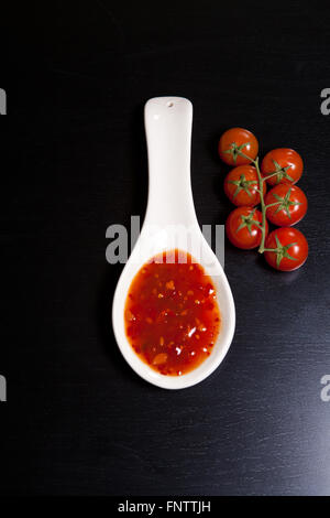 Spicy tomato sauce en saucière près de tomates cerises sur une dar Banque D'Images