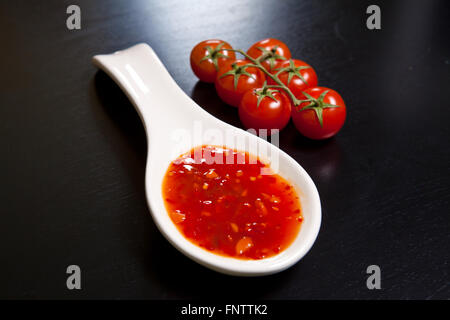 Spicy tomato sauce en saucière près de tomates cerises sur une dar Banque D'Images