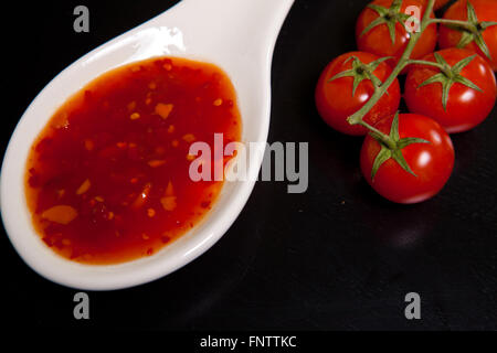 Spicy tomato sauce en saucière près de tomates cerises sur une dar Banque D'Images