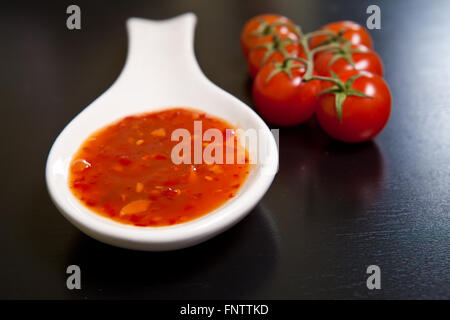 Spicy tomato sauce en saucière près de tomates cerises sur une dar Banque D'Images