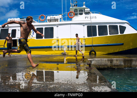 Les adolescents de sauter dans l'eau à côté du quai de Vaitape Bora Bora, îles de la société, Polynésie Française, Pacifique Sud. Banque D'Images