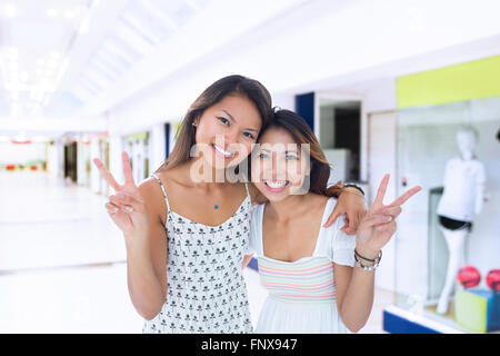 Image composite de deux jeunes femmes sourire faisant un geste de paix Banque D'Images