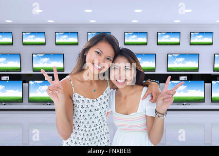 Image composite de deux jeunes femmes sourire faisant un geste de paix Banque D'Images