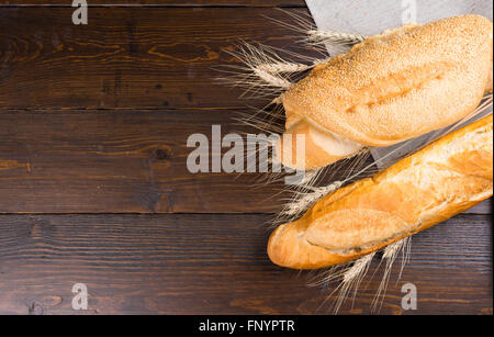 Deux types de baguettes avec des fentes sur le dessus et les graines de sésame dans les tiges de blé entier entre plus de table brun foncé Banque D'Images