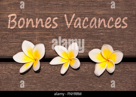 Texte Bonnes vacances (sens bon été en français) avec plancher en bois sur plumeria flower background Banque D'Images