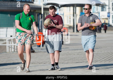 Pays de Galles Aberystwyth UK, mercredi 16 mars 2016 UK weather : trois jeunes hommes portant des shorts de marcher le long de la promenade, profiter de la chaleur du soleil de printemps à Aberystwyth , l'ouest du pays de Galles au Royaume-Uni. D'un autre jour de ciel clair et le soleil chaud la température atteint un maximum de 13ºC Crédit : Keith morris/Alamy Live News Banque D'Images