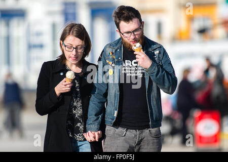 Pays de Galles Aberystwyth UK, mercredi 16 mars 2016 Météo France : un jeune couple eating glaces , marchant le long de la promenade, profiter de la chaleur du soleil de printemps à Aberystwyth , l'ouest du pays de Galles au Royaume-Uni. D'un autre jour de ciel clair et le soleil chaud la température atteint un maximum de 13ºC Crédit : Keith morris/Alamy Live News Banque D'Images