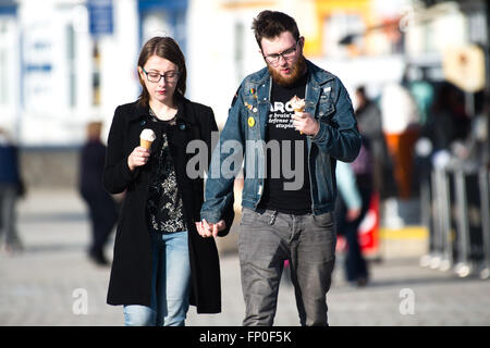 Pays de Galles Aberystwyth UK, mercredi 16 mars 2016 Météo France : un jeune couple eating glaces , marchant le long de la promenade, profiter de la chaleur du soleil de printemps à Aberystwyth , l'ouest du pays de Galles au Royaume-Uni. D'un autre jour de ciel clair et le soleil chaud la température atteint un maximum de 13ºC Crédit : Keith morris/Alamy Live News Banque D'Images