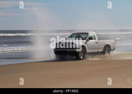 La conduite de camions à travers l'eau sur une plage Banque D'Images