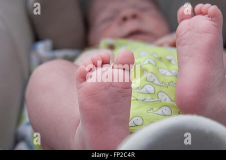 Chubby pieds d'un bébé nouveau-né garçon dans la poussette pendant que sur une promenade à l'extérieur dans la rue Banque D'Images