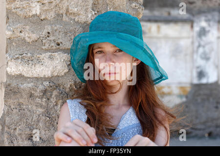 Fille aux cheveux roux avec un chapeau de soleil turquoise à sérieusement, portrait, Italie Banque D'Images