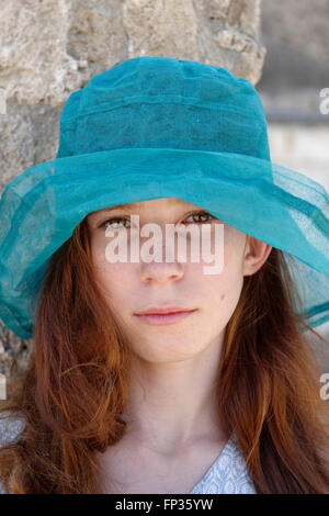 Fille aux cheveux roux avec un chapeau de soleil turquoise à sérieusement, portrait, Italie Banque D'Images