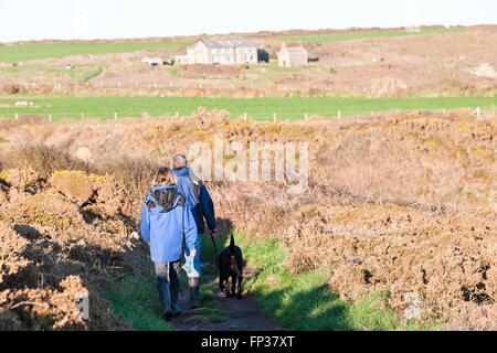 Dog Walkers randonnées autour de St's Bay. Non En arrière-plan Non St's Retreat et non sur la Chapelle St le littoral du Pembrokeshire, près de St David's. Non St West Wales, Royaume-Uni l'Europe. Mars. Non St's Retreat a été construit en 1929 et d'aujourd'hui la Chapelle St Non a été construit en style authentique début-Celtique en 1934. Banque D'Images