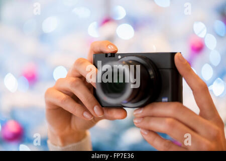 Femme prend une photo avec un appareil photo compact en face d'un arbre de Noël Banque D'Images