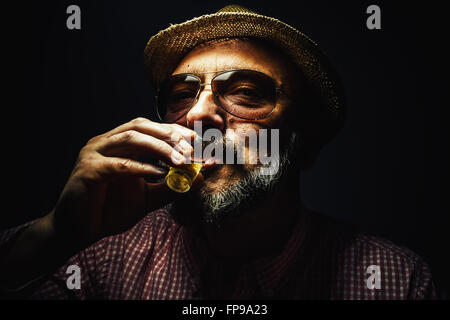 Heureux l'homme d'âge moyen de boire une boisson alcoolisée. Banque D'Images