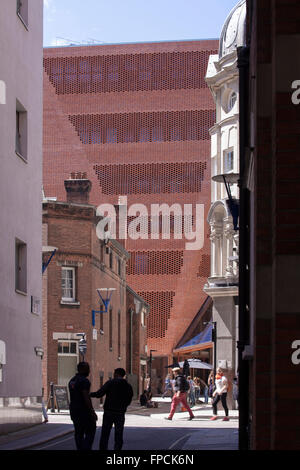 L'angle de mur en brique et en verre forte entrée de la LSE Student Center conçu par O'Donnell & Tuomey Architects, vu au fond d'une ruelle qui a personnes milling à ce sujet. Banque D'Images