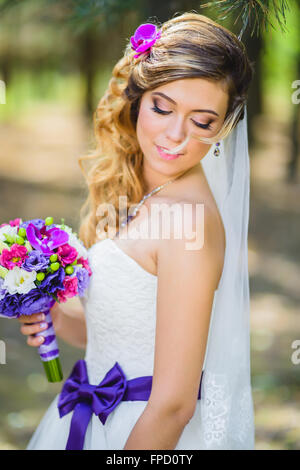 La jeune fille dans une robe de mariage avec purple bow Banque D'Images
