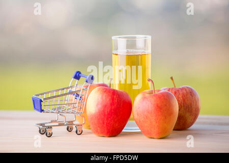 Pommes, jus de pomme et un panier sur une table en bois, extérieur Banque D'Images