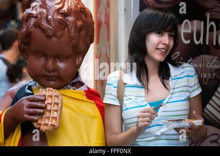 Une femme qui pose à côté d'un gofres wafles ou publicité, Bruxelles, Belgique. Une statue en plâtre de la statue du Manneken Pis en dehors d'un Waff Banque D'Images