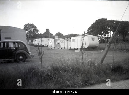 Années 1950, historiques, un certain nombre de petites caravanes ou remorques tractées ou aigu sans rouler dans le champ, certains de façon permanente sur les plates-formes d'herbe, England, UK. Banque D'Images
