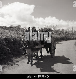 Années 1950, photo historique par J Allan Cash, d'un couple irlandais rural voyageant sur une ruelle de campagne sur leur âne et leur chariot dans l'ouest de l'irlande. Banque D'Images