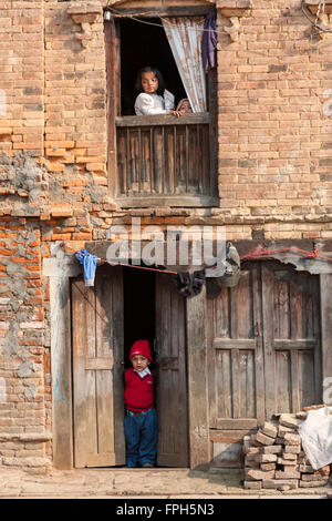 Le Népal, Patan. Dans la fenêtre fille, garçon en porte. Banque D'Images