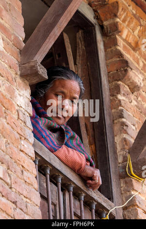 Le Népal, Patan. Femme regardant par sa fenêtre. Banque D'Images